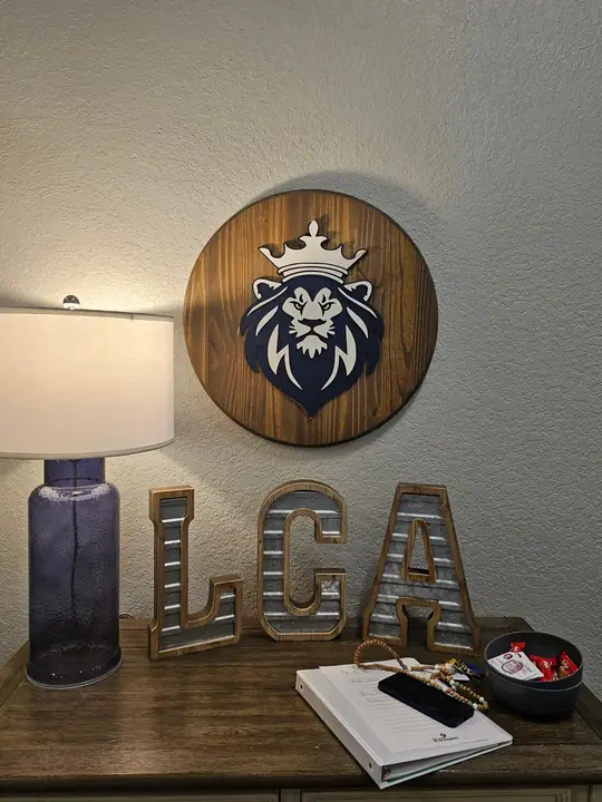 Round wooden lion plaque above a table with a lamp and metal letters